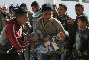 A Palestinian youth carries an injured boy into a hospital in Khan Yunis after an Israeli military operation. (AFP/Said Khatib) 