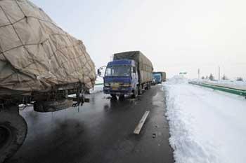 Some trucks drive slowly into the entrance of the Heliuye highway in Anhui Province, east China, Jan. 29, 2008. Most region in Anhui stopped snowing on Jan. 29. After all day working of removing ice and snow, most highways in Anhui reopened at present. (Xinhua Photo)