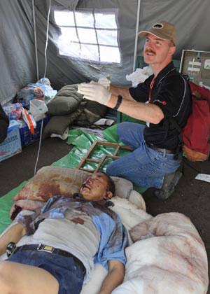 The U.S. medical doctor who called himself as Sun Baian treats an injured in the quake-hit Beichuan County in southwest China's Sichuan Province, May 14, 2008.(Xinhua Phot