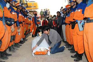 A man weeps by the body of his dead wife as members of the Japanese rescue team stand around him at Qiaozhuang Town of Qingchuan County in the quake-stricken southwest China's Sichuan Province, May 17, 2008. Japanese earthquake rescuers found two corpses in a collapsed six-floor building in Qiaozhuang at 7:25 am after 16 hours rescue operation. (Xinhua/Li Tao)