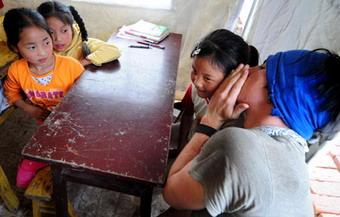 A volunteer from the United States talks to a child during an English class in a makeshift classroom in quake-affected Anxian County of Sichuan Province May 29, 2008. Two US volunteers arrived at the county on Thursday to help with English lessons. [Xinhua]