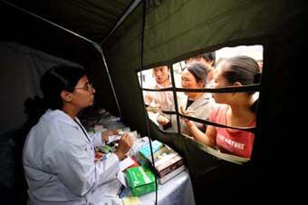 A member (L) of the Pakistani medical team explains to people the usage of the medicine in the Wudu District of Longnan City, northwest China's Gansu Province, June 2, 2008. The 28-member Pakistani medical team has set up a tent hospital in quake-hit Longnan after it arrived in the city on May 29.(Xinhua Photo)
