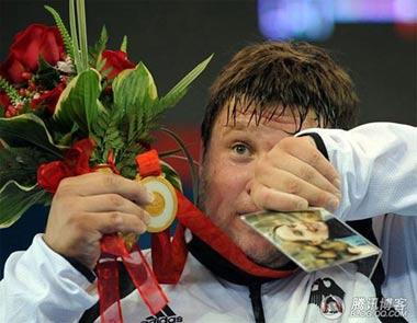 Matthias Steiner is holding his late wife's picture high which he is standing on the podium.