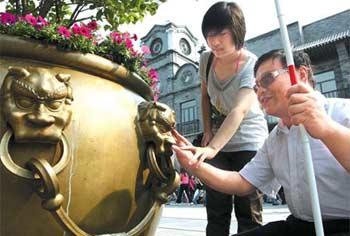 Shi&nbsp;Jing&nbsp;(right)&nbsp;touches&nbsp;a&nbsp;giant&nbsp;bronze&nbsp;flowerpot&nbsp;on&nbsp;Qianmen&nbsp;Street&nbsp;yesterday.(China&nbsp;Daily&nbsp;Photo/Wang&nbsp;Jing)