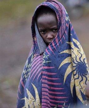 A child covers himself from the rain while standing roadside at the entrance to a camp for Internally Displaced People on the outskirts of the provincial city of Goma. The United Nations accused rebels and pro-government militia Saturday of war crimes in eastern Democratic Republic of Congo, as government troops reinforced their front-line positions.(AFP/Roberto Schmidt)