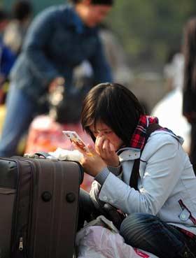 A woman applies makeup while waiting outside Guangzhou Railway Station for train back home in Guangzhou, south China's Guangdong Province, January 4, 2009. Guangzhou Railway Station has seen a sharp rise in the number of travellers since the New Year holiday started on January 1. An early travel rush with travellers mainly migrant workers and college students return home for Spring Festival holiday. [Xinhua]
