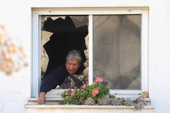 A man inspects the damage to a building caused by Katyusha rockets fired from Lebanon, in Nahariya, northern Israel, Jan. 8, 2009. Several rockets pounded northern Israel Thursday morning, causing light injuries. Israeli forces fought back shortly by firing mortars across the border. (Xinhua/Moran Mayan)