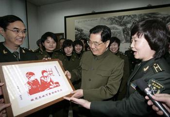 Hu Xuzhe (R), an instructor of local communication station of China's People's Liberation Army (PLA) General Staff Headquarters, present a paper cut work to Chinese President Hu Jintao (C, front), who is also General Secretary of the Communist Party of China (CPC) Central Committee and chairman of the Central Military Commission (CMC), in Beijing, capital of China, Jan. 21, 2009. (Xinhua/Ma Zhancheng) 