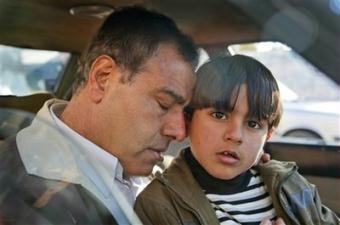 Dr. Ezzeldeen Abu al-Aish, a Palestinian doctor and peace activist who trained in Israel and became a regular fixture on Israeli television, rests his head on his son Abdullah, 6, in a car before traveling to Israel with his children, near his house in Jebaliya, in the northern Gaza strip, Wednesday, Jan. 21, 2009. Three of his daughters and a niece were killed by an Israeli shell which struck his house, and he returned to Gaza Wednesday to collect his remaining children.(AP Photo/Ben Curtis)