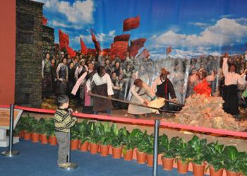 A boy watches a simulated scenario featuring serfs burning feudal documents produced in old Tibet after the Democratic Reform at an exhibition marking the 50th anniversary of the Democratic Reform in Tibet Autonomous Region in Beijing, Feb. 25, 2009. (Xinhuanet Photo)