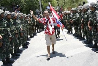 A&nbsp;Thai&nbsp;anti-government&nbsp;protester&nbsp;leaves&nbsp;Government&nbsp;House&nbsp;through&nbsp;a&nbsp;line&nbsp;of&nbsp;soldiers&nbsp;in&nbsp;Bangkok,&nbsp;Thailand,&nbsp;Tuesday,&nbsp;April&nbsp;14,&nbsp;2009.&nbsp;(AP&nbsp;Photo/Wong&nbsp;Maye-E)