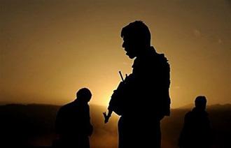 An Afghan policeman keeps watch as colleagues inspect the site of a suicide attack in March 2009.(AFP/File/Shah Marai)