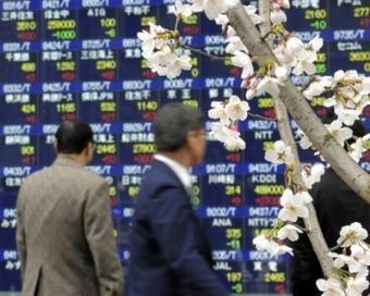 Cherry blossom blooms in front of the window of a securities company in Tokyo on April 1 as businessmen check stock prices. Tokyo stocks jumped 3.74 percent on Thursday after the Japan's ruling party approved a stimulus spending plan that amounts to more than 15.4 trillion yen ((154 billion dollars).(AFP/File/Toshifumi Kitamura)
