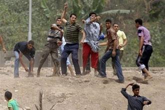 Egyptian youths throw rocks towards police during clashes over a mass cull of pigs in Cairo. Egyptian riot police clashed with stone-throwing pig farmers who were trying to prevent their animals being taken away for slaughter as part of a mass nationwide cull. (AFP/Khaled Desouki)