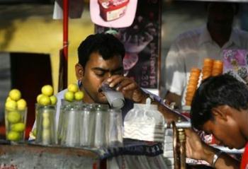 A person quenches his thirst by drinking lime water from a road-side vendor, in New Delhi, India, Friday, May 1, 2009. A scorching heat wave has swept through several Indian states leading to at least 18 deaths, the weather department and officials said Friday.