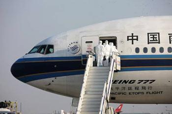 Inspectors walk aboard the chartered plane from Mexico to check the health of Chinese citizens from Mexico after the plane arrived in Shanghai on May 6, 2009. The chartered plane sent to fetch Chinese citizens from Mexico arrived in Shanghai Wednesday afternoon, with 98 passengers and 21 crew members on board. (Xinhua/Xing Guangli)