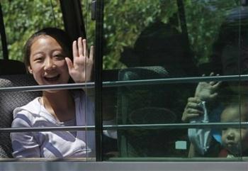A woman waves after being released from quarantine at a holiday camp where they were held for a week in Hong Kong Thursday, May 7, 2009. At least 28 of the 34 passengers who flew from Shanghai to Hong Kong with the Mexican man confirmed as the territory's first and only swine flu patient were released Thursday afternoon. Another 347 guests and staff quarantined in the Metropark Hotel in Wanchai will be released Friday evening.