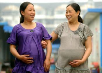 Zhao Xiaoqing (L) and another pregnant woman walk between prefab rooms of Mum's Home, a psychological assistance institution in Dujiangyan City, southwest China's Sichuan Province, May 8, 2009. The 37-year old Zhao Xiaoqing lost her son in the May 12 massive earthquake in southwest China, but now she is seven-month pregnant. Her son would be 13 years old if he were alive this year. Like Zhao Xiaoqing, many women carrying kids gathered at Mum's Home to make paper roses for the Mother's Day as gifts to the people who helped them during hard times. According to government statistics, there are over 6,000 families that lost their children in the May 12 earthquake and have the intention to raise another one, but the aftershocks, the pain of losing relatives and their ages are major obstacles. [Photo: Xinhua]