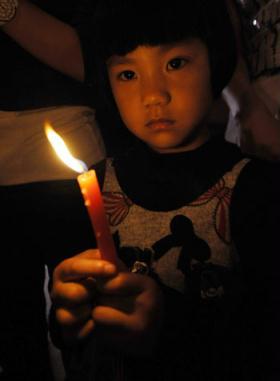 A child holds a candle during an activity to commemorate the victims of the fatal May 12, 2008 Wenchuan earthquake, in Zhengzhou, capital of central China's Henan Province, May 12, 2009.  (Xinhua Photo)