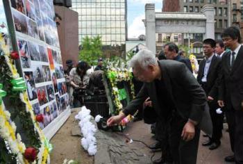 An elder man presents flowers to the victims who died in the devastating May 12, 2008 Wenchuan earthquake in the Chinatown of New York City, the United States, May 12, 2009. A mourning ceremony sponsored by Chinese federation of East America on Tuesday to mark the first anniversary of the May 12 , 2008 earthquake. (Xinhua/Wang Jiangang)