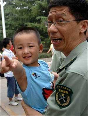 Lang Zheng (L), known as the "Salute Boy", poses for a picture in the arms of an officer of Tangdu Hospital while leaving the hospital after two months of treatment, in Xi'an, capital of northwest China's Shaanxi Province, July 27, 2008. Lang, from the Qushan Township Kindergarten of Beichuan Qiang Autonomous County in southwest China's Sichuan Province, was rescued from the debris after the May 12 Wenchuan earthquake. After being put on a stretcher, the injured and fragile boy slowly raised his right hand and saluted his rescuers in gratitude. The moment was captured by a photographer and moved the whole nation. His fractured left arm and partly amputated left fingers have been recovering well during the two months at Tangdu Hospital.
