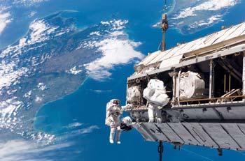 S116-E-05983 (12 Dec. 2006) --- Backdropped by a colorful Earth, astronaut Robert L. Curbeam, Jr. (left) and European Space Agency (ESA) astronaut Christer Fuglesang, both STS-116 mission specialists, participate in the mission's first of three planned sessions of extravehicular activity (EVA) as construction resumes on the International Space Station. The landmasses depicted are the South Island (left) and North Island (right) of New Zealand.