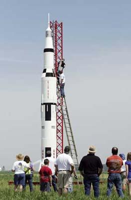 Onlookers watch as rocket builder Steve Eves (bottom, on ladder) installs an electronic control panel in his one-tenth scale Saturn V rocket prior to a successful launch in Price, Maryland April 25, 2009. (Xinhua/Reuters Photo)